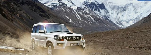 White jeep driving on a dirt road with mountains in the background